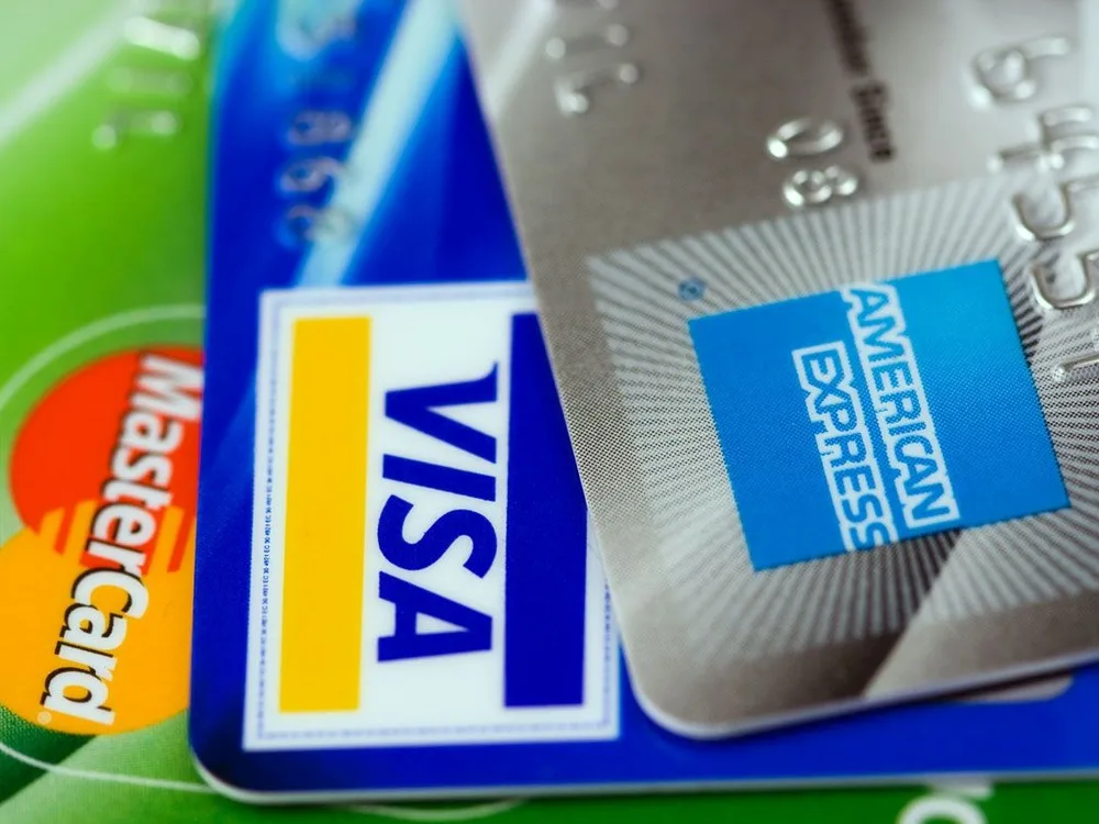 Three credit cards fanned showing Mastercard, Visa, and American Express logos on a clean white background