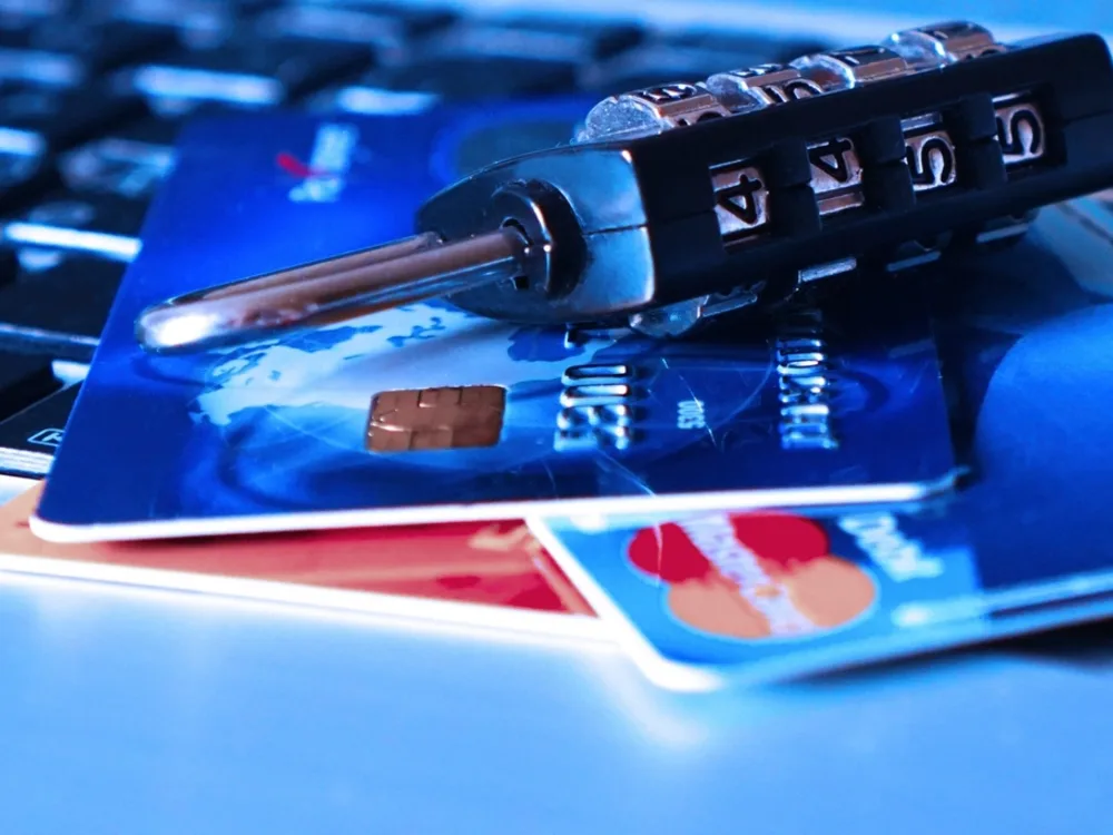 Two Mastercard credit cards on a laptop keyboard with a combination lock — credit card security editorial concept